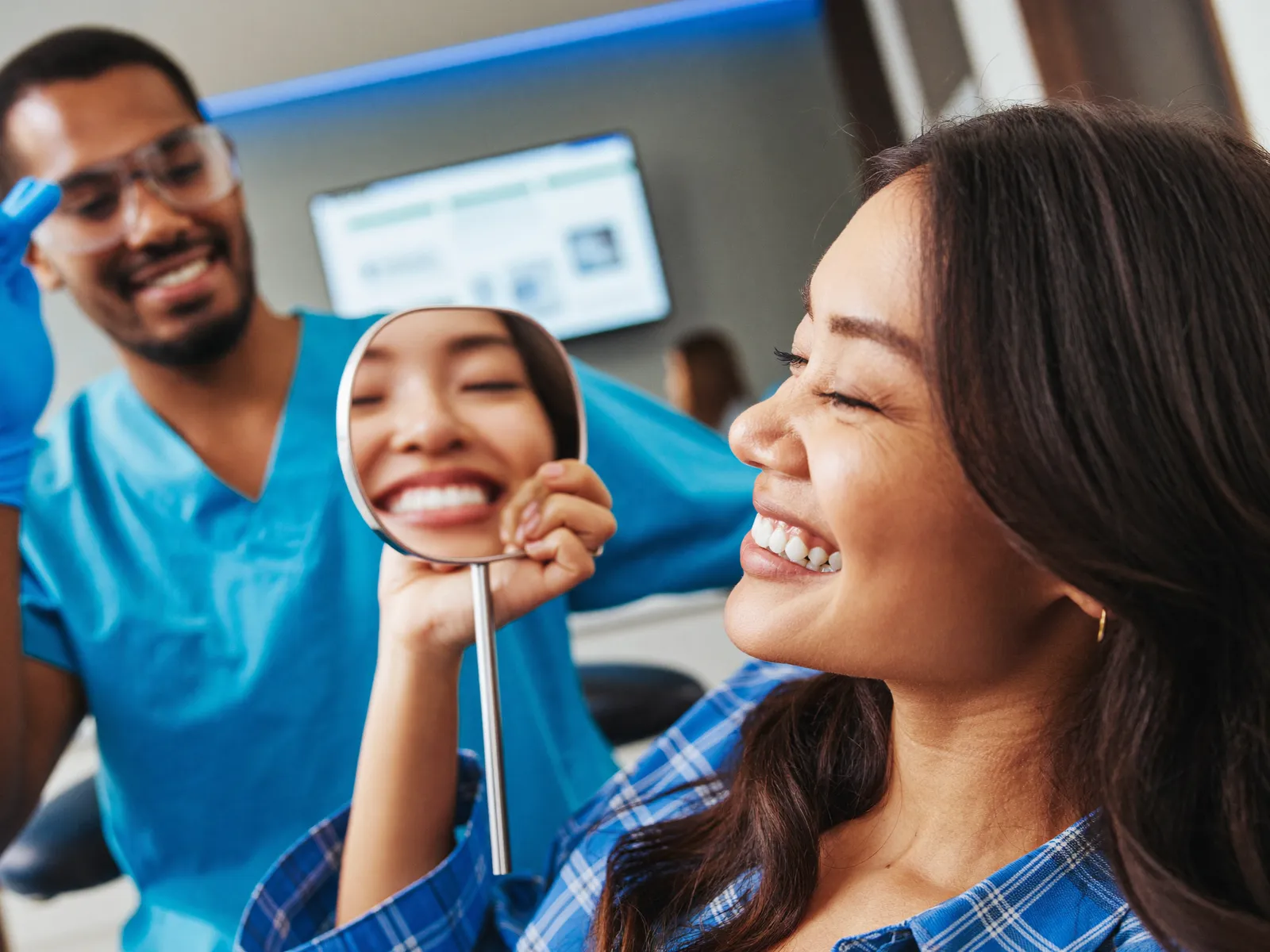 Uma mulher admirando o sorriso no espelho no dentista
