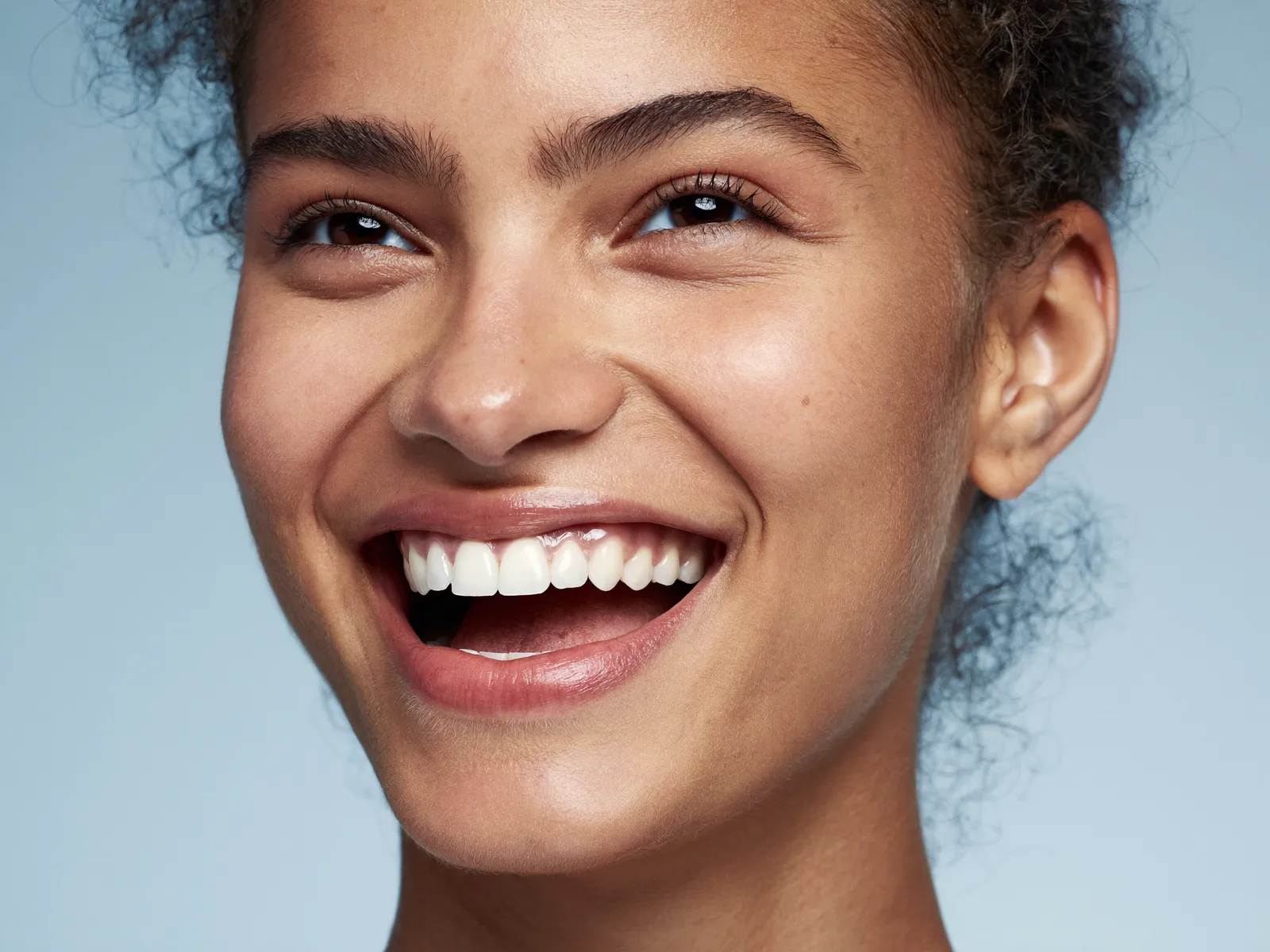 Uma mulher rindo com um sorriso brilhante e saudável